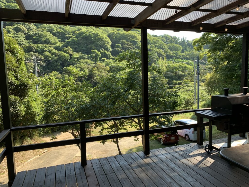 屋根つきの広いデッキと、その先に広がる緑の谷