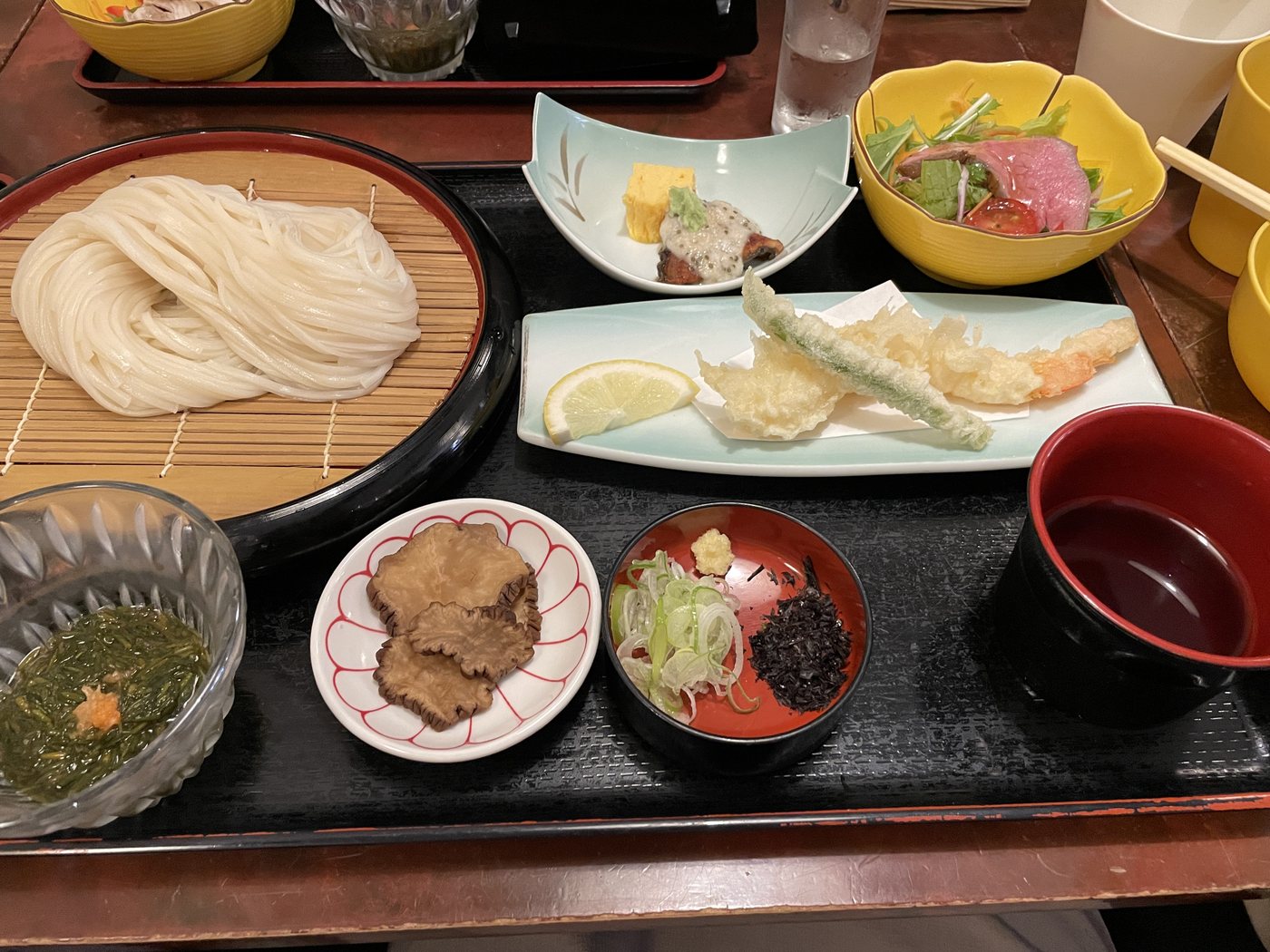 無限堂の稲庭うどん御膳。いぶりがっこ、天ぷら、じゅんさいなどが並ぶ