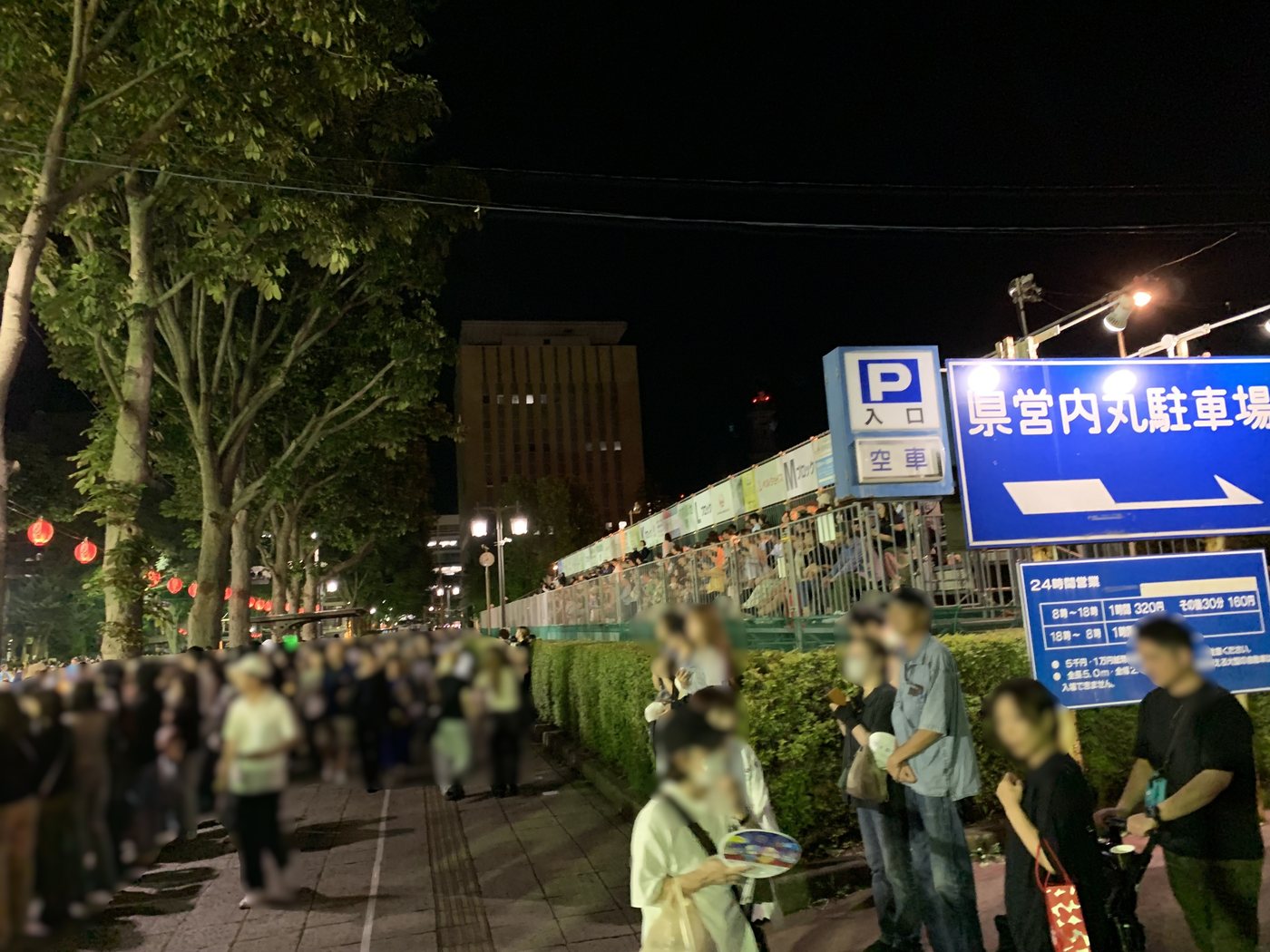 祭りの終了後、県営内丸駐車場の看板の前を帰路につく人の流れ